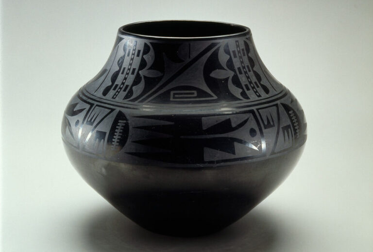 Blackware pottery vessel with a wide mouth and bulbous body that tapers to a narrow base. The pot is adorned with geometric tribal patterns presented in a matte finish on the glossy surface.