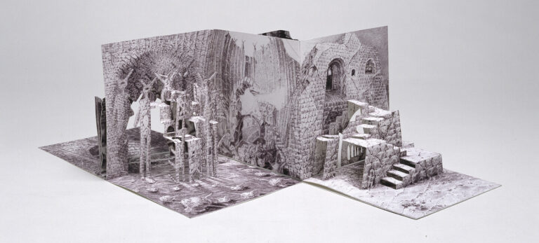 A pop-up book opens to reveal intricate, three-dimensional black-and-white illustrations of ancient, crumbling stone ruins with staircases, columns, and archways, set against a plain white background.
