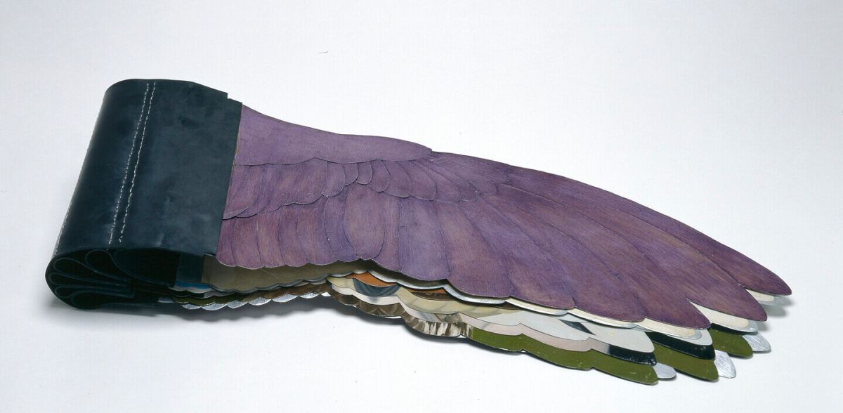 A sculptural book with pages shaped like bird wings, featuring the painted purple cover and black spine displayed closed against a white background.
