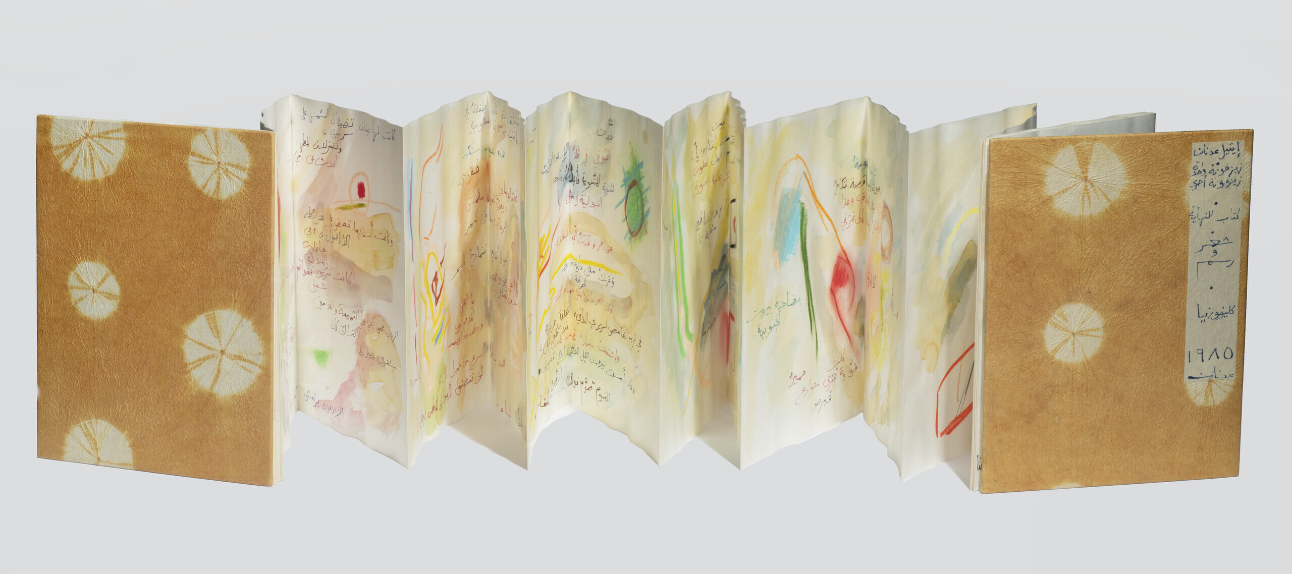 An accordion book lays open horizontally on a white background. The front and back covers are orange and the internal pages contain colorful illustrations and Arabic text in watercolor and ink.