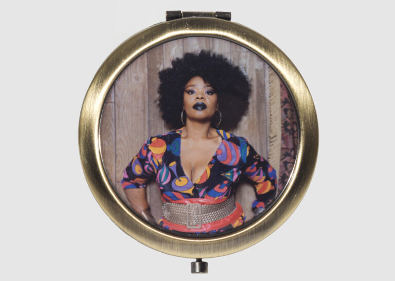 Mickalene Thomas, Pocket mirror (front), 2016 (based on Mickalene Thomas, Din Facing Forward, 2012); Brushed bronze with epoxy-coated artwork, 2 5/8 in. diameter; Produced by Third Drawer Down; National Museum of Women in the Arts, Gift of Steven Scott, Baltimore, in honor of National Museum of Women in the Arts Chief Curator, Kathryn Wat; Photo by Lee Stalsworth