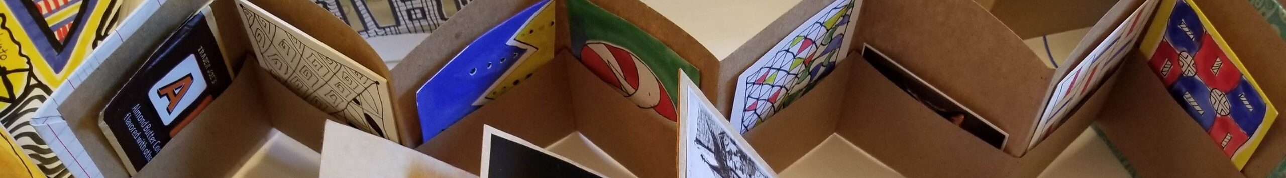 A birds-eyed view of a variety of artists books showing a variety of folded paper and works of art.