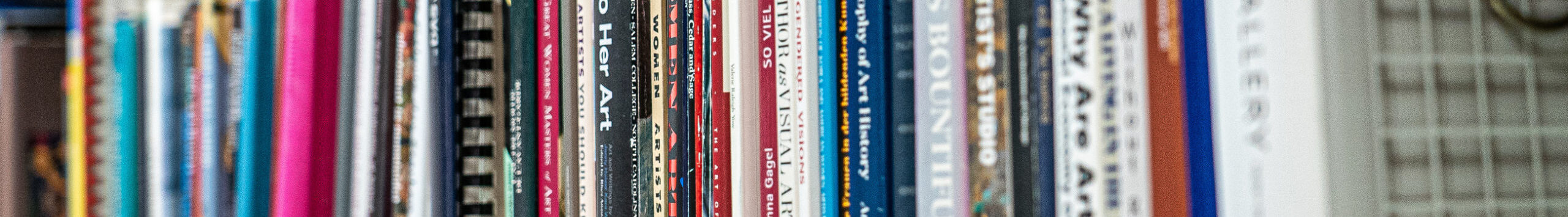 A bookshelf packed with colorful books about women artists.
